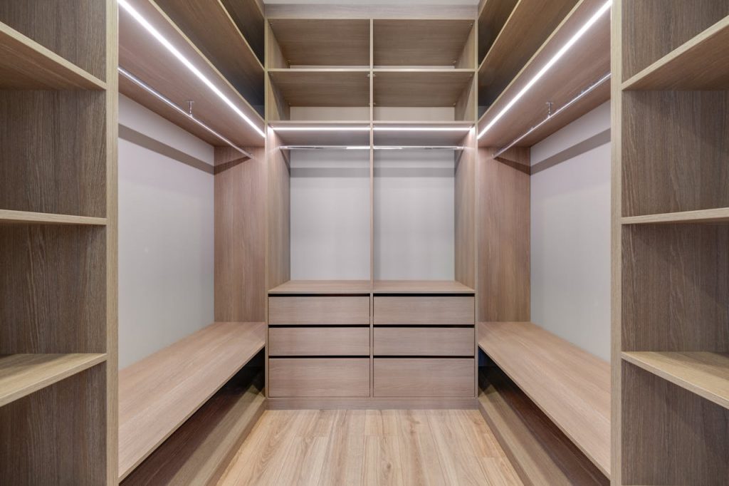 pexels photo 11701120 Spacious walk-in closet with wooden shelves and LED lighting creates a minimalist and modern design.
