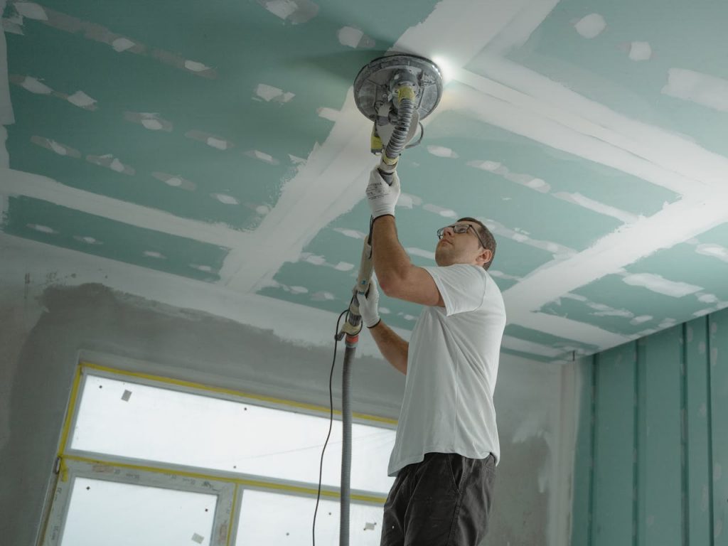 pexels photo 6474343 A professional worker sanding the ceiling during a home renovation project. Indoor construction setting.